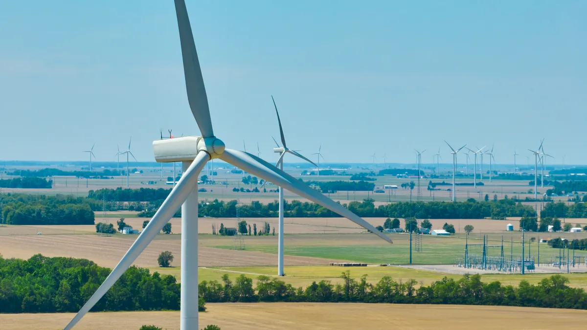 Aerial close up of wind turbine in Ohio with a wind farm and substation in the background.