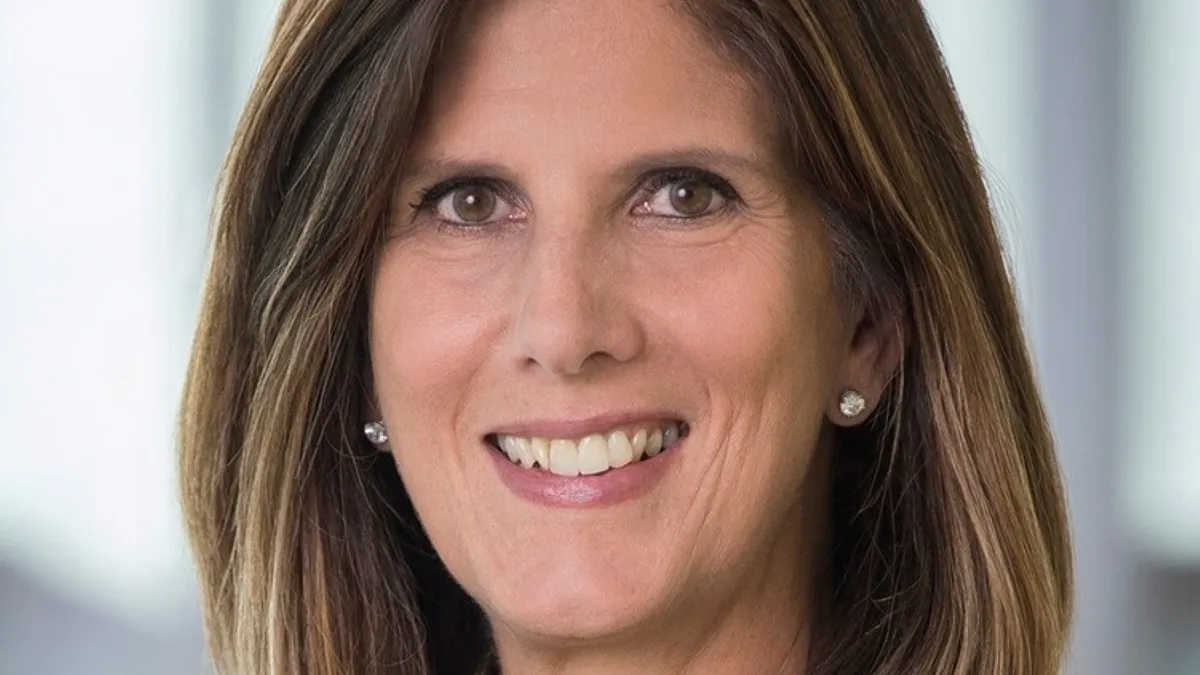 A headshot of a person with chin-length hair and earrings.