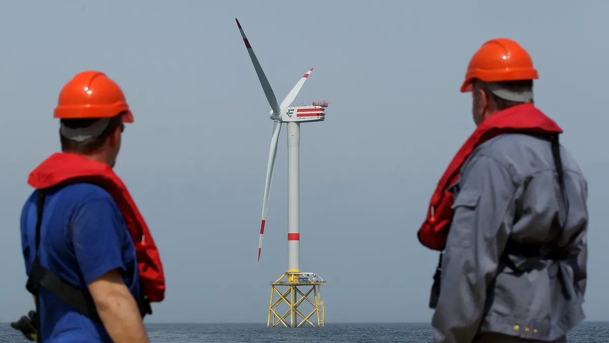 Workers look at offshore wind turbines.