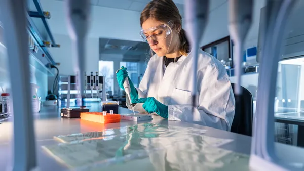 Person doing lab work with a tube and vials.