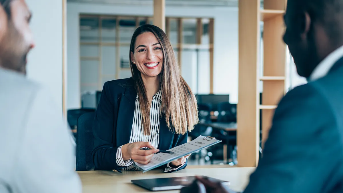 A general counsel smiles while sitting in their office