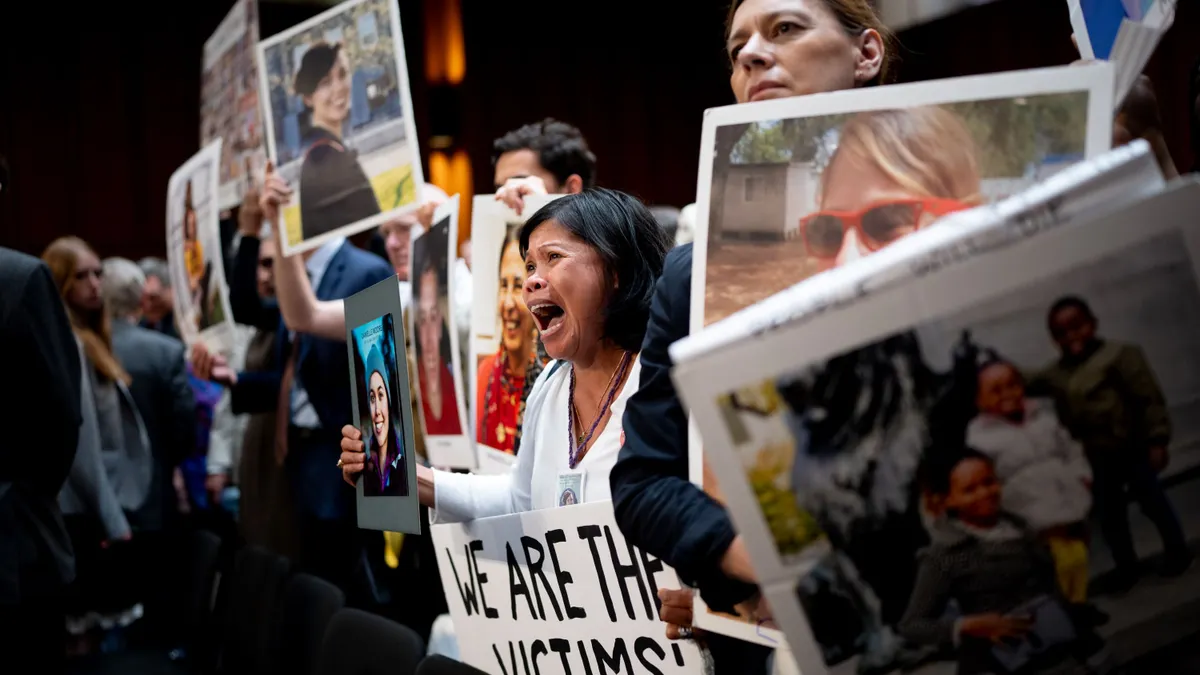 A group of peoplle holding up signs and photos of their deceased love ones.