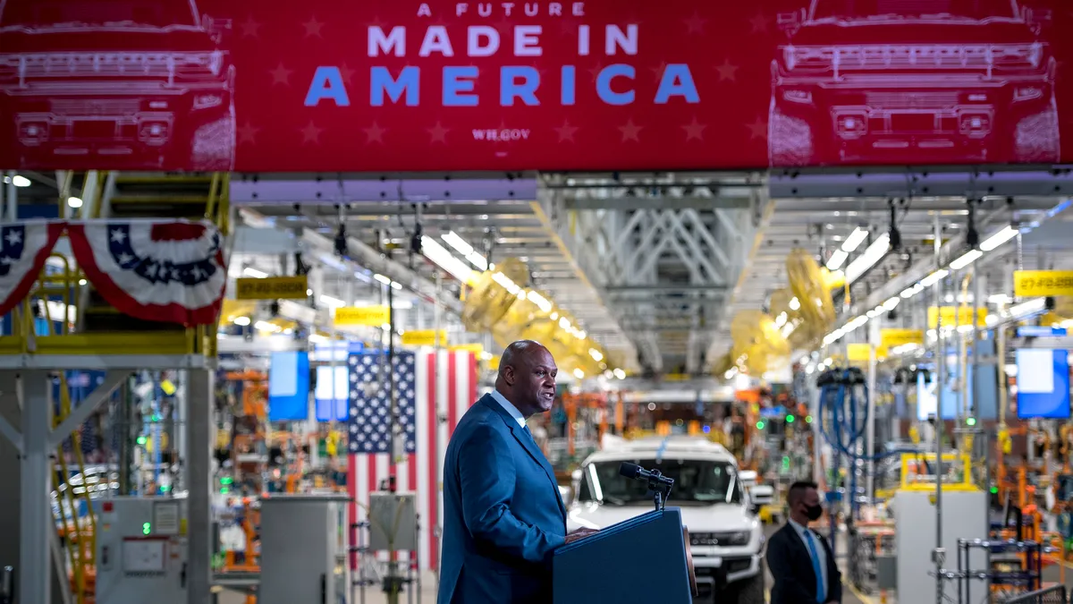 United Auto Workers President Ray Curry stands at a podium in an automotive assembly plant under a sign that reads, "A future made in America."