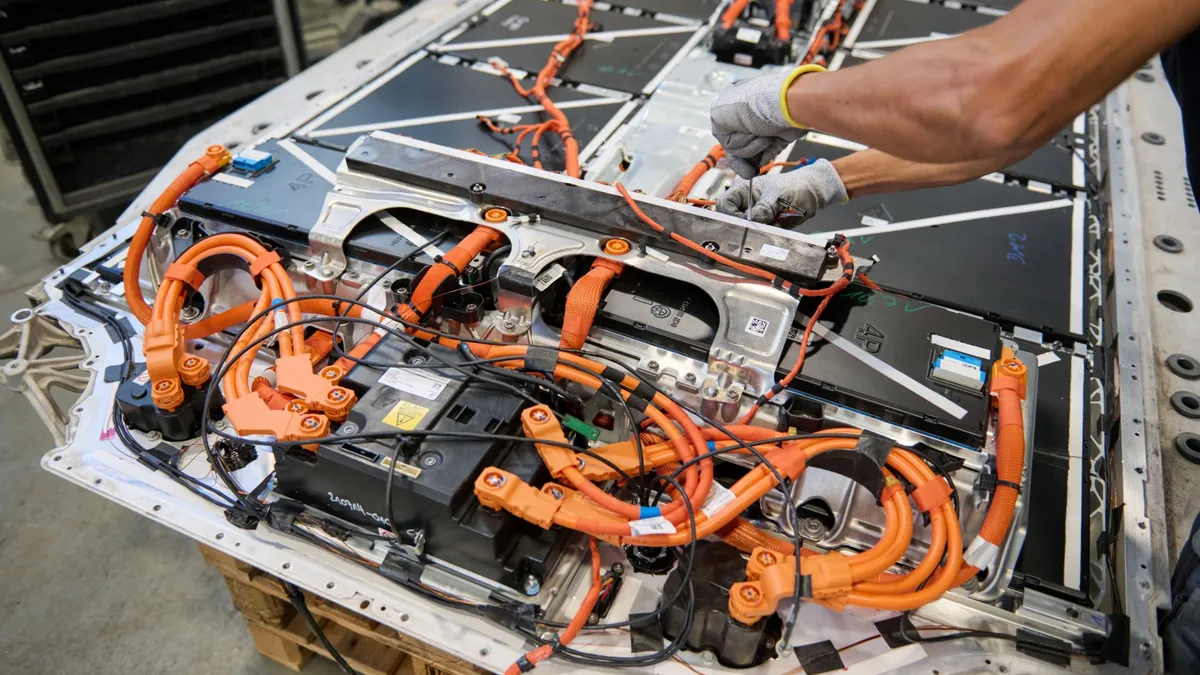 A worker disassembles a high-voltage battery removed from a BMW vehicle.