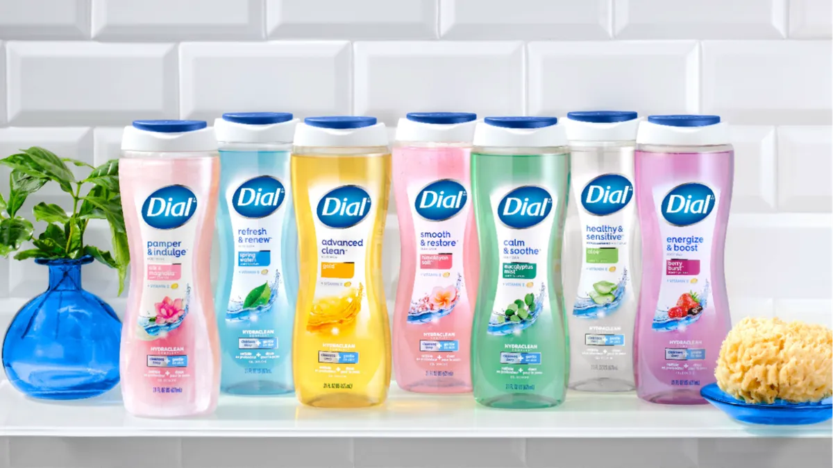 Seven bottles of different scents of Dial body wash lined up next to one another on a countertop.