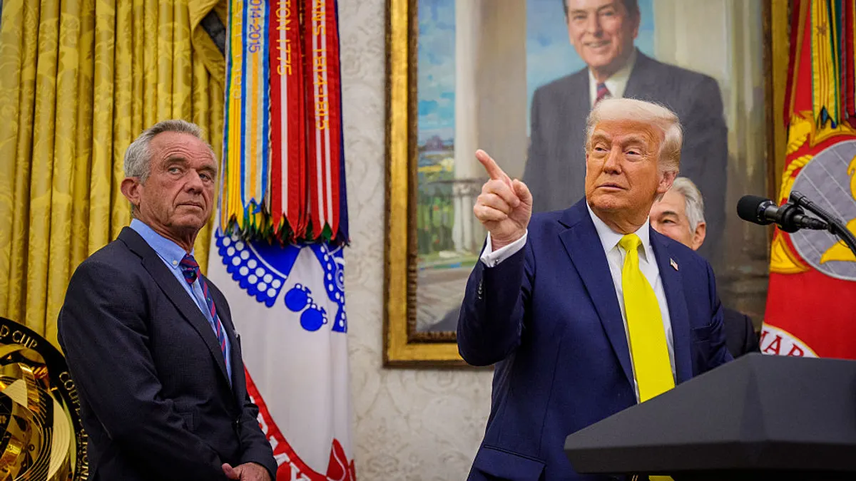 President Donald Trump stands at podium with Robert F. Kennedy Jr. on his left side