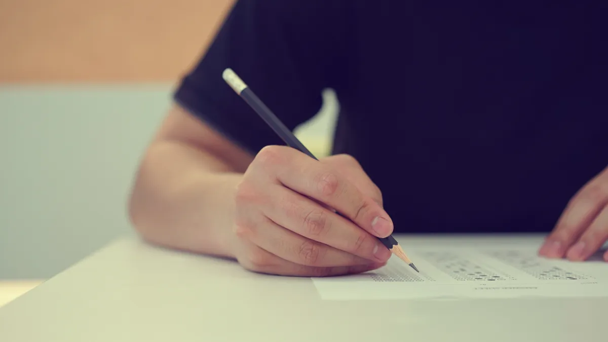 A high school student takes a standardized test with a pencil.