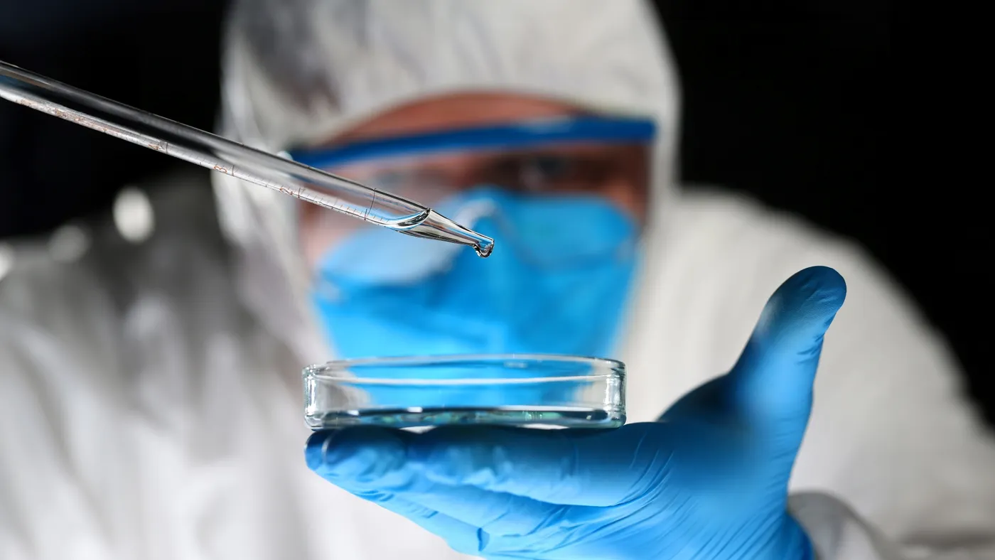 Chemist looks at test tube with yellow liquid biological research closeup.