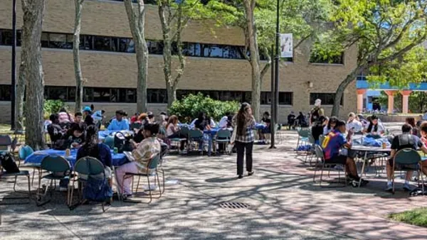 People are shown gathering outside of a building at Kingsborough Community College in Brooklyn, New York.