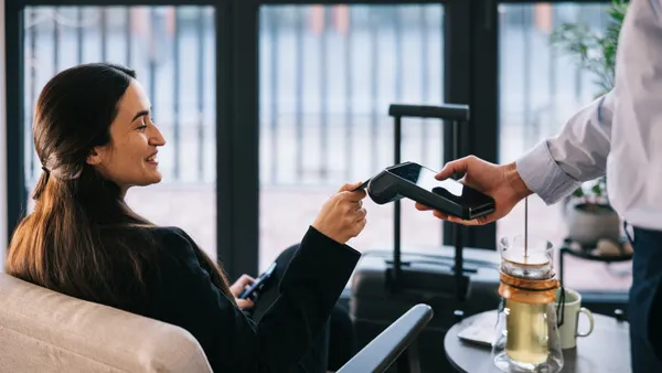 Businesswoman pays with her credit card at a airport business lounge.