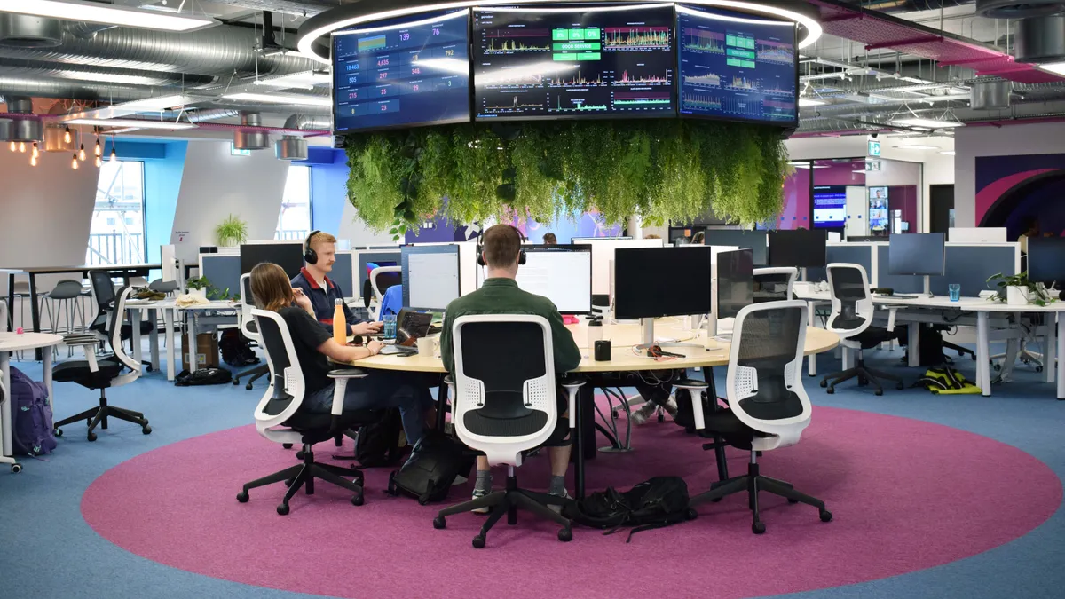 Workers sitting at a round table in a modern office with growing plants above