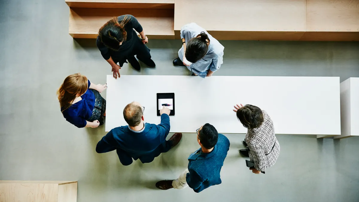 Overhead view of business colleagues discussing project on digital tablet