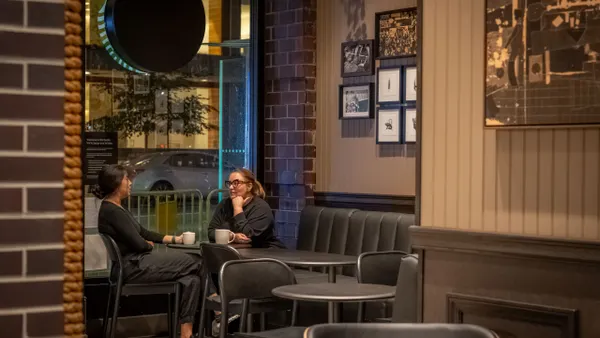Two people sit at a table in a dark cafe with warm lighting.