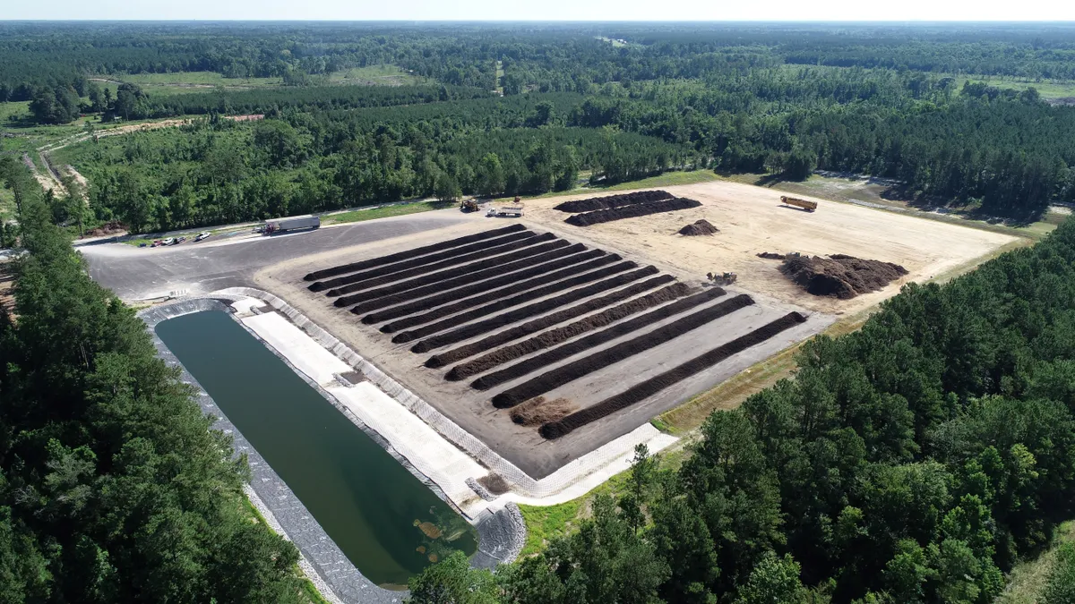 An aerial view of an outdoor facility with more than a dozen long earthen mounds and a wastewater pond