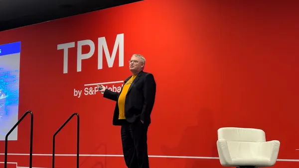 A man stands on a stage in front of a red background