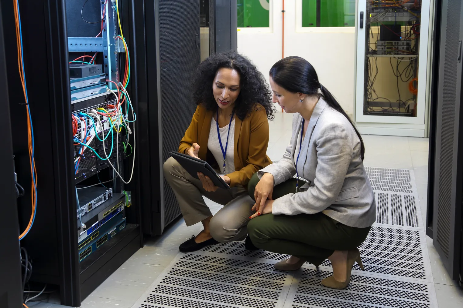 Adult women in data center checking cables and whole network, server setup and programing mainframe through digital tablet.