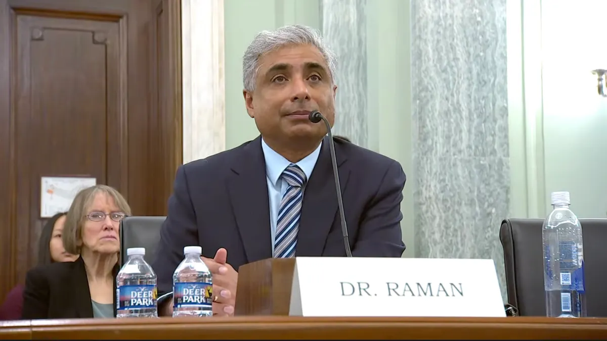 Arvind Raman sits at a desk in front of a microphone