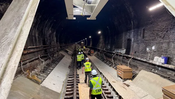 A group of construction workers walk down a tunnel.