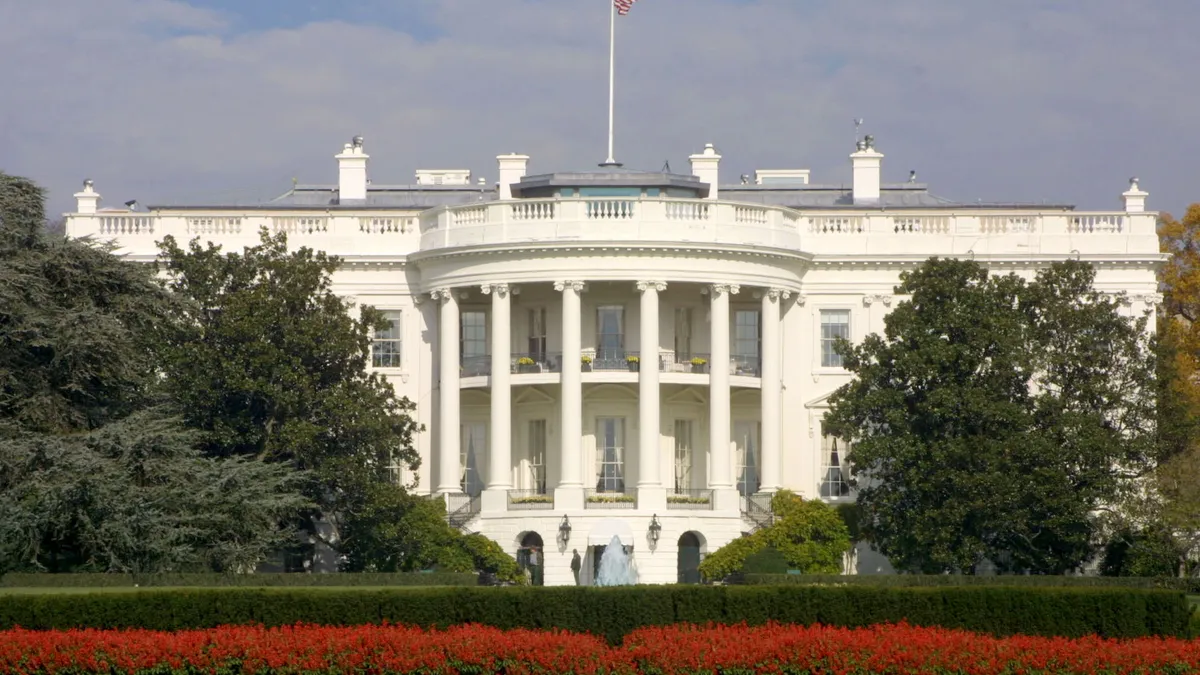 An American flag flies atop the White House on a partly cloudy day in Washington, DC.