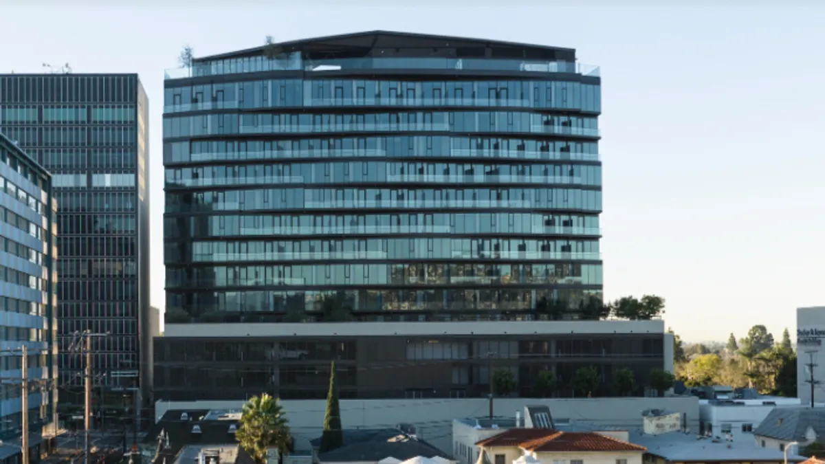 A large, convex-shaped apartment building is in the focus and foreground.