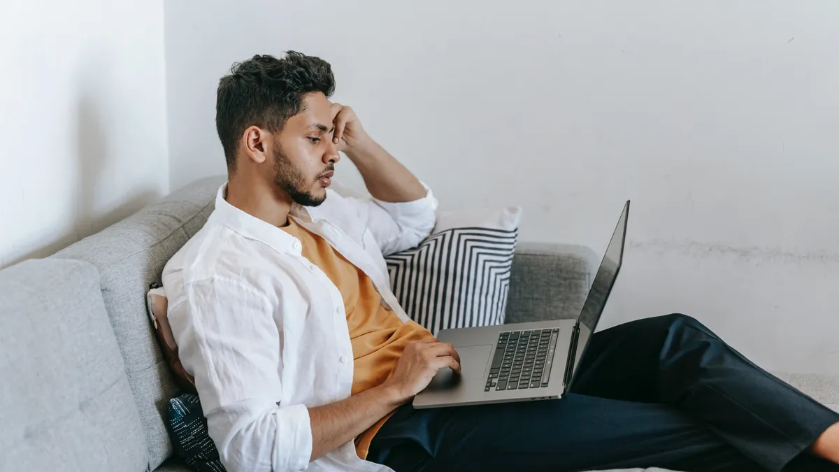 A person types on their laptop in distress