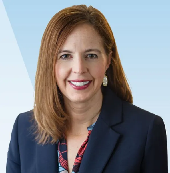 Woman with long straight brown hair in a dark blue blazer.