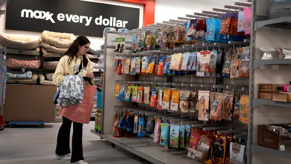 A shopper browses an aisle of snacks with the sign "maxx every dollar" behind her.
