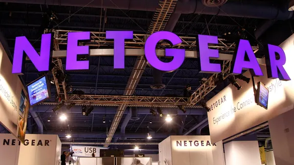 The word "Netgear" is spelled out in large purple letters attached to a metal bar hanging from a ceiling