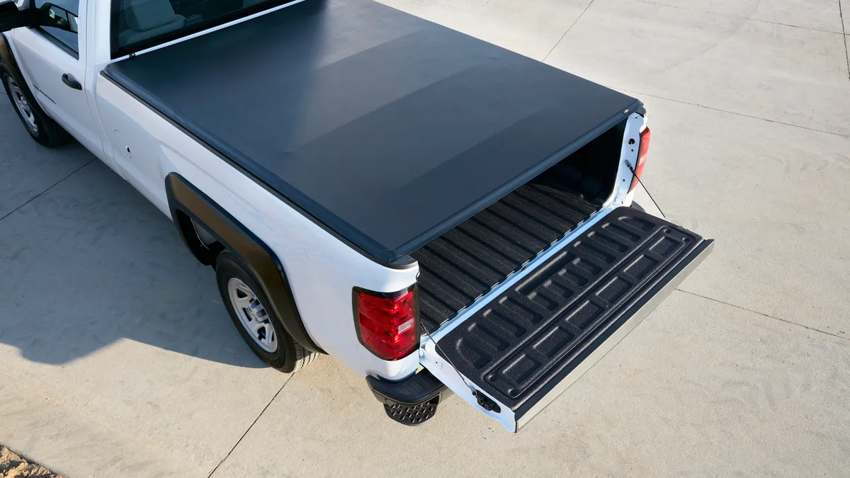 A white Chevrolet Silverado with a black cover on back.