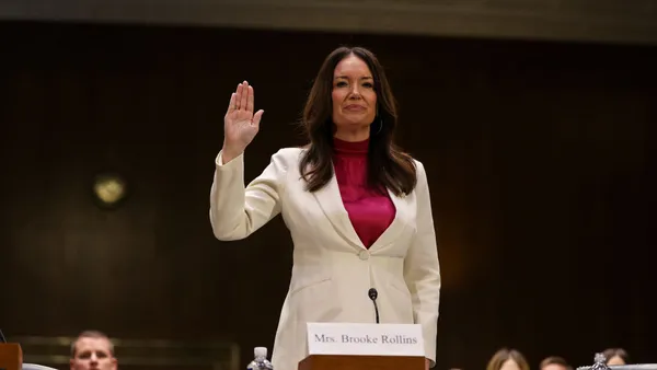 Brooke Rollins stands with her hand raised