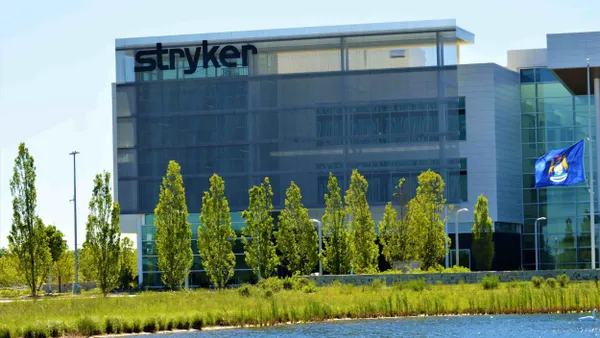 A picture of a large building with the name "Stryker" across it and a pond with a swan in the foreground.