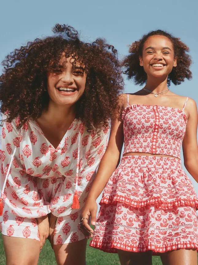 Two people wearing red and white patterned items from Target's collaboration with Roller Rabbit.