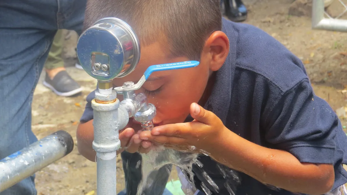 A little boy drinks water from a Global Brigades project completed in 2019 in Nicaragua.