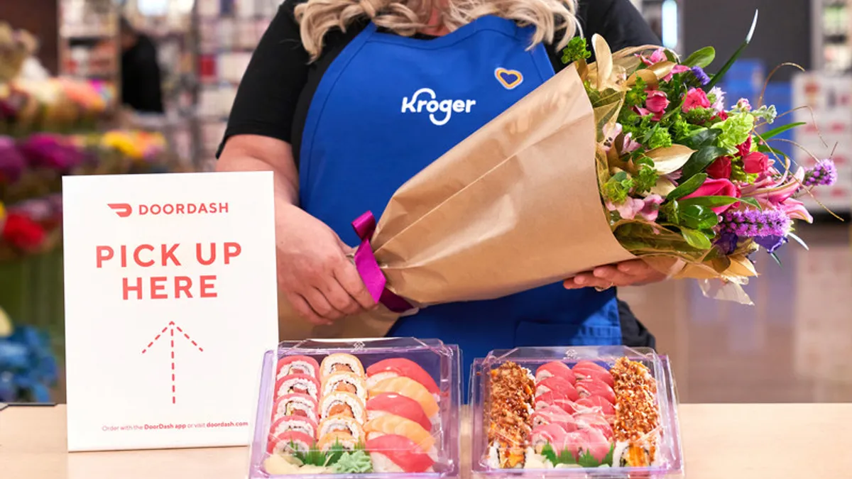 Image of a Kroger worker holding flowers in front of sushi packages by a "DoorDash pick up here" sign