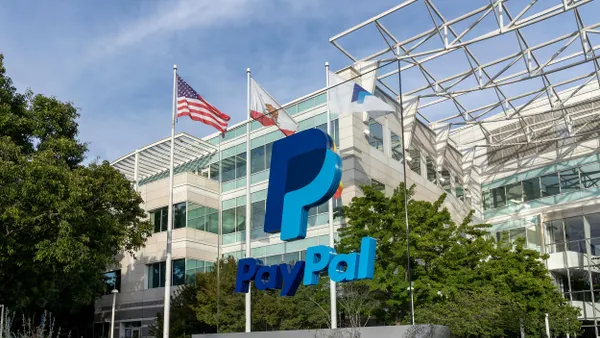 A large Paypal logo and sign are seen from a low angle, and a commercial building entrance is behind it. 