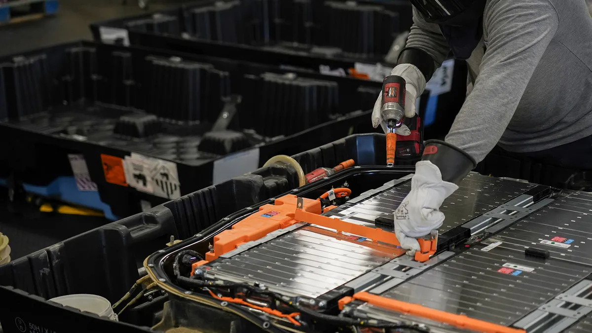 A worker dismantles an electric vehicle battery for recycling.