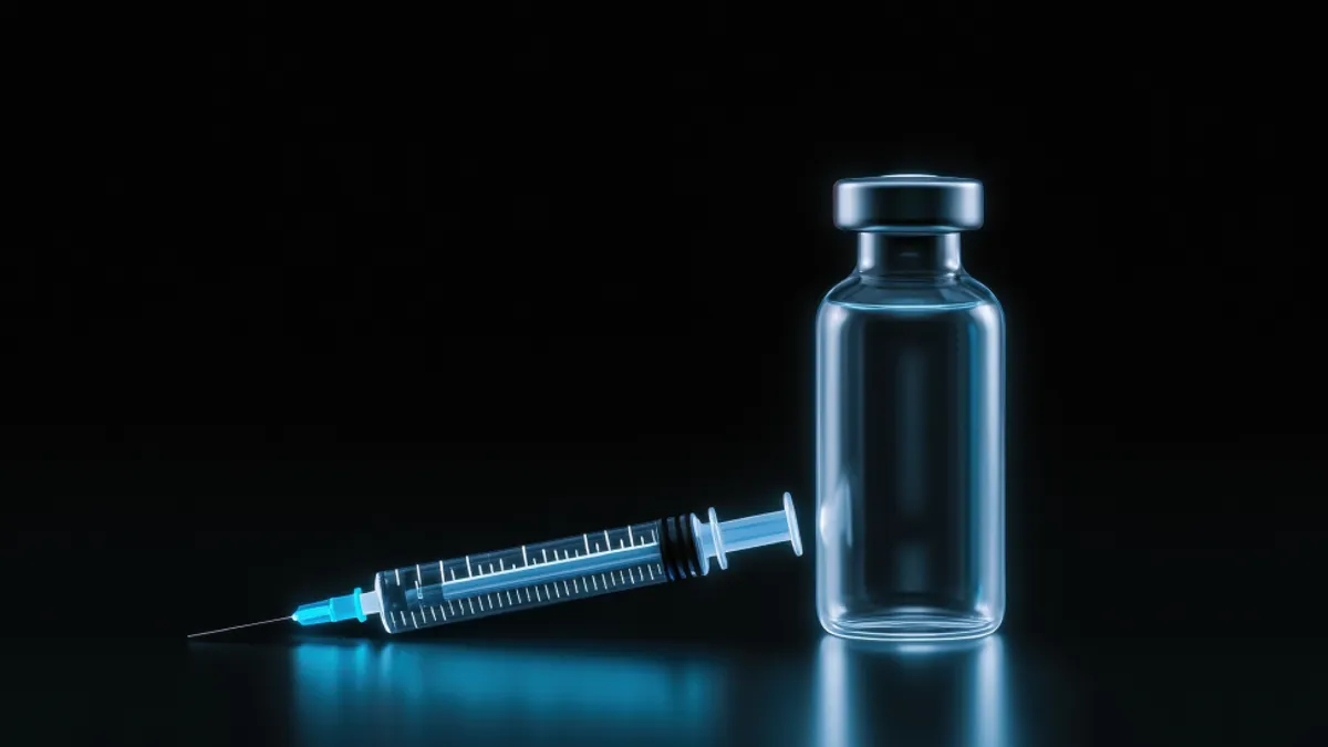 Syringe and a small glass vial on a black background