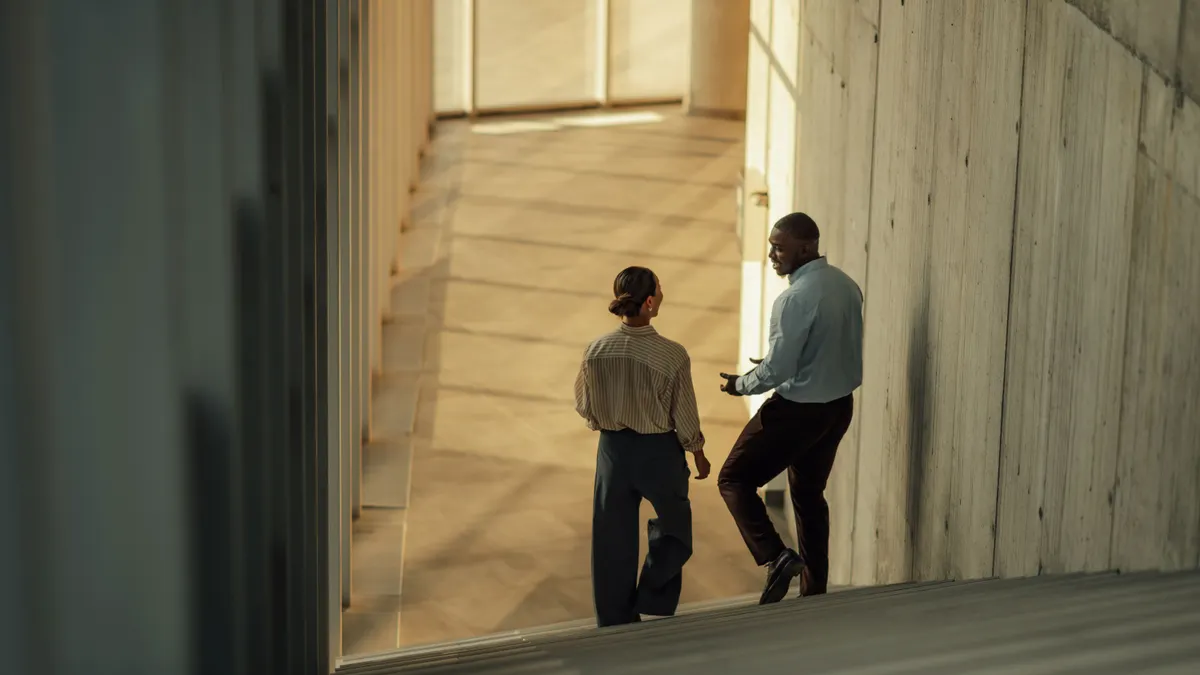 Businesspeople walking and talking on stairs in modern office building