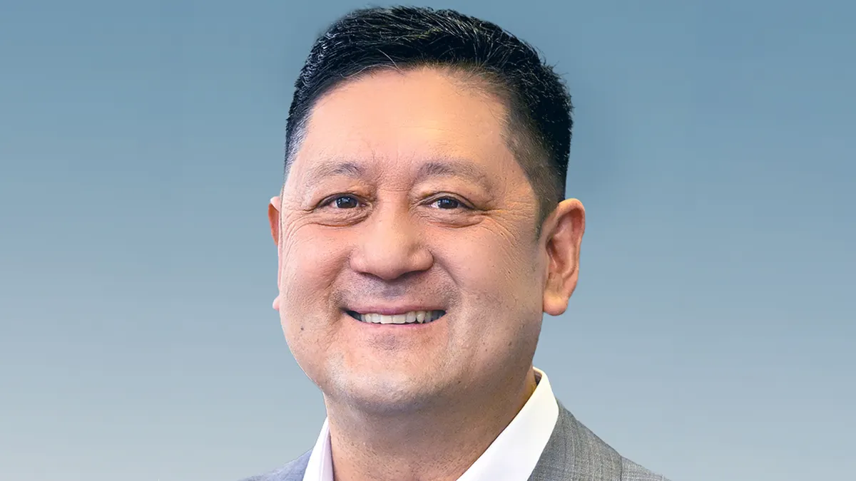 A headshot of John Kao, the CEO of Alignment Healthcare, against a blue background