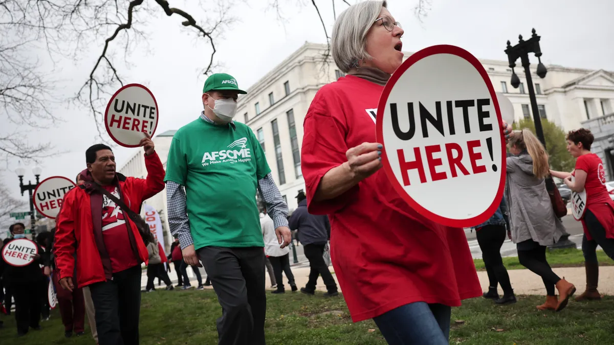 Workers hold signs reading "UNITE HERE."