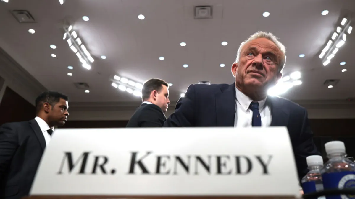 Robert F. Kennedy Jr. stands over a desk with his name tag.