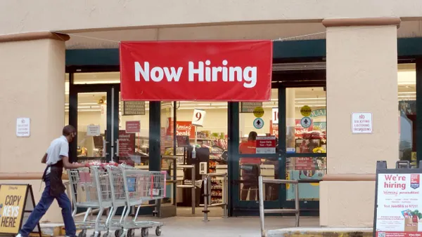A Now Hiring sign hangs near the entrance to a Winn-Dixie Supermarket on September 21, 2021 in Hallandale, Florida.