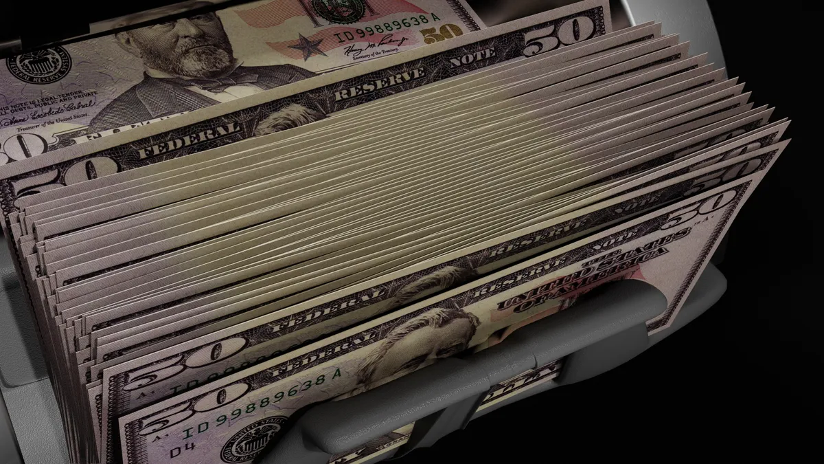 Fifty-dollar bills are counted by a money counting machine.