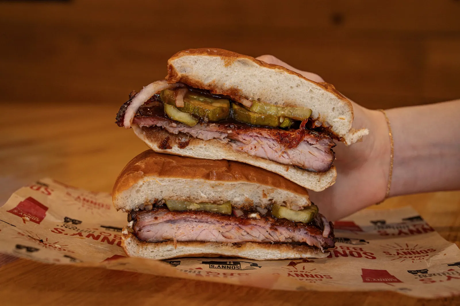A photograph of a hand holding up a rib sandwich