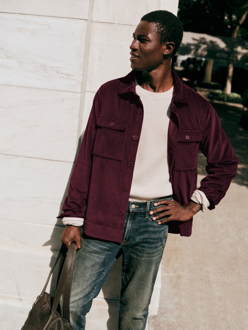 A person in a white T-shirt and maroon button-down shirt looks off to the side.