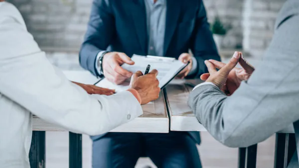 Shot of three business persons filling in paperwork in an office.