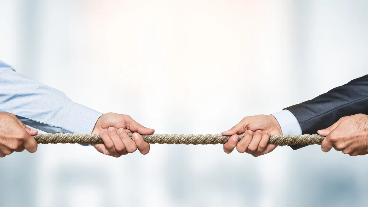 Two businessmen pulling on a rope at opposite ends