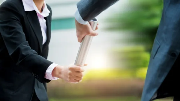 Business people pass the baton outdoors.