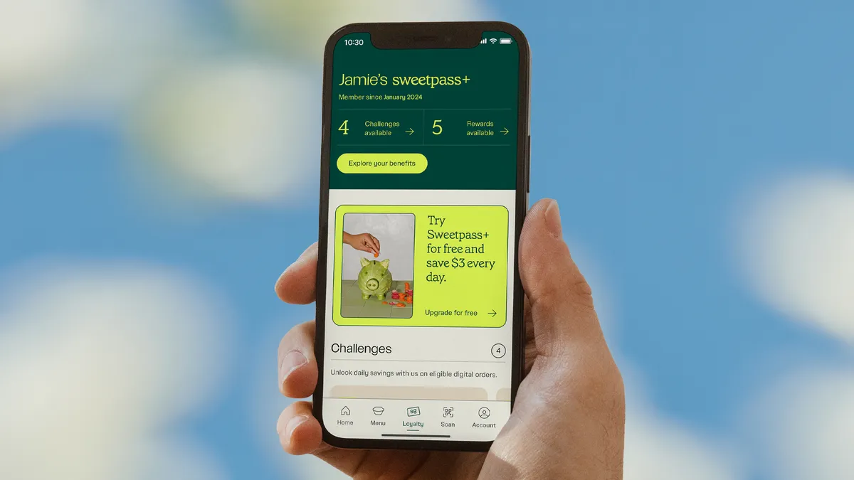 A hand holds a smartphone with Sweetgreen's loyalty program on the screen