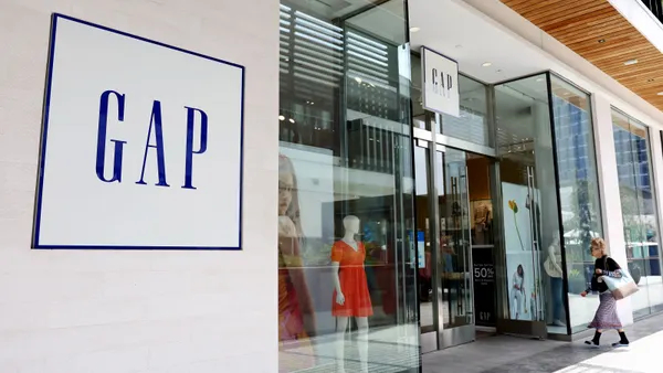 A person walks into a retail store. The word "Gap" is displayed outside the store.